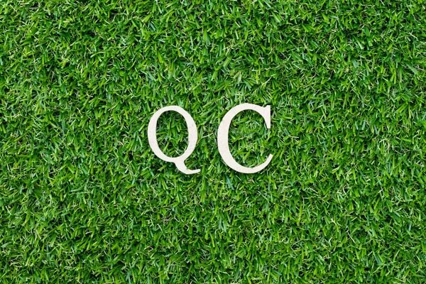 Trä alfabet bokstav i ord QC (förkortning av kvalitetskontroll) på grönt gräs bakgrund — Stockfoto