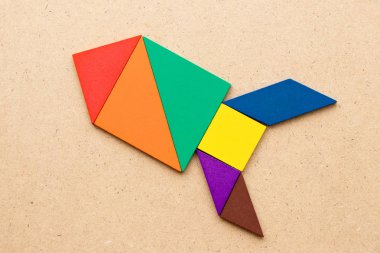 Renk tangram bulmacanın (kavram yeni deneyimi için başlangıç proje kadar ahşap arka plan üzerinde roket veya füze şeklinde)