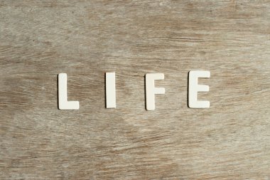 Ahşap arka planda kelime yaşamında alfabe harfi