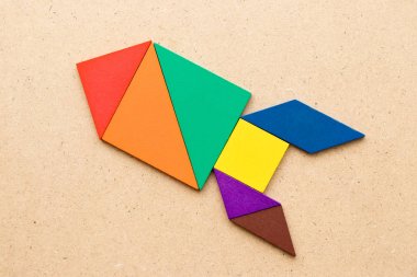 Renk tangram bulmacanın (kavram yeni deneyimi için başlangıç proje kadar ahşap arka plan üzerinde roket veya füze şeklinde)