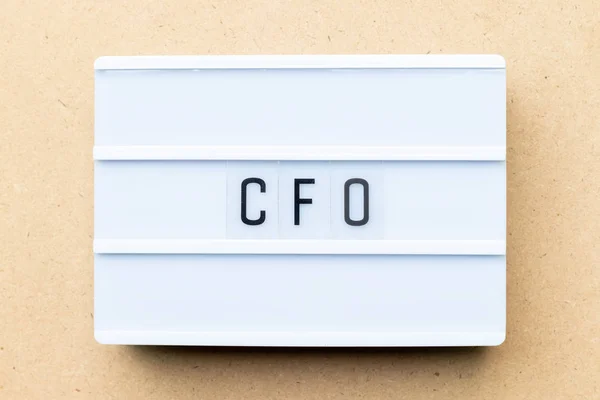 Lightbox branco com palavra CFO (abreviatura de Chief Financial Officer) sobre fundo de madeira — Fotografia de Stock