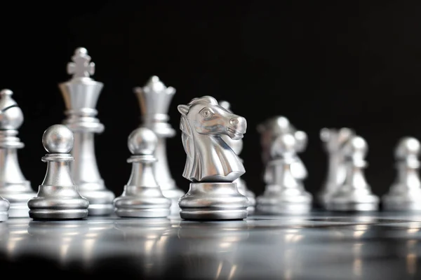 Silver knight chess piece stand in front of team on black background (Concept for leadership, management)