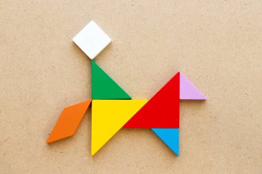 Adam ahşap arka plan üzerinde at şekli binmek Renk tangram bulmaca