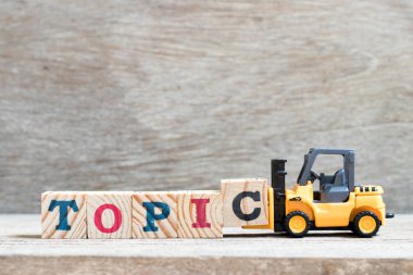 Oyuncak forklift ahşap arka plan üzerinde kelime konu tamamlamak için harf blok c tutun