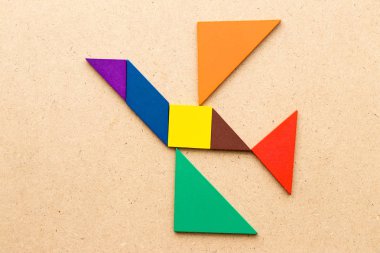 Kuş şekli ahşap arka plan üzerinde uçan renk tangram bulmacanın