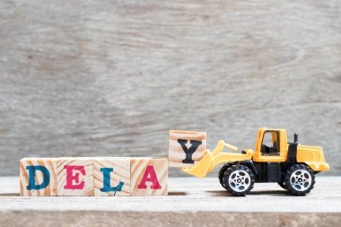 Oyuncak buldozer kelime gecikme ahşap arka plan üzerinde tamamlamak için mektup blok y tutun