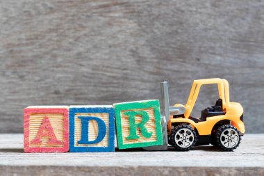 Oyuncak forklift tutun mektup blok ahşap arka plan üzerinde kelime Adr (kısaltma olumsuz uyuşturucu reaksiyon) tamamlamak için R