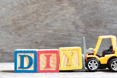 Word DIY tamamlamak için oyuncak forklift tutun mektup blok Y (kısaltma kendin yap) ahşap arka plan üzerinde