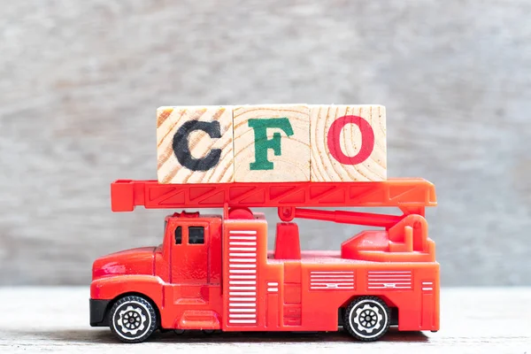 Caminhão de bombeiros vermelho segurar bloco de letras na palavra CFO (Abreviatura de Chief Financial Officer) sobre fundo de madeira — Fotografia de Stock