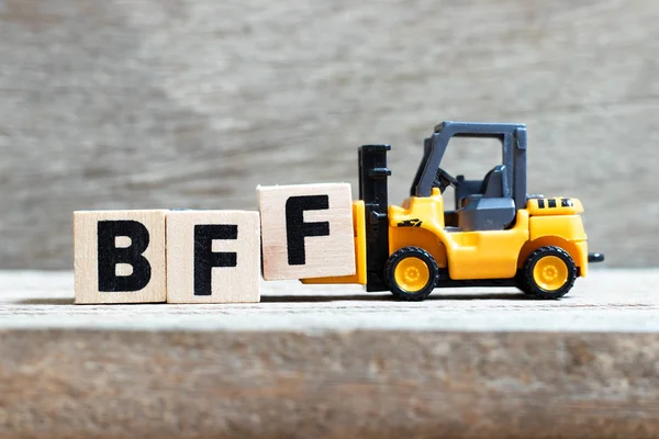 Toy forklift ahşap arka plan üzerinde kelime Bff (sonsuza kadar en iyi arkadaş kısaltması) tamamlamak için harf blok f tutun — Stok fotoğraf