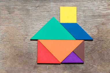 Ahşap arka planda ev veya ev şeklinde renk tangramı