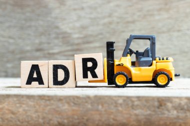 Oyuncak forklift tutun mektup blok ahşap arka plan üzerinde kelime Adr (kısaltma olumsuz uyuşturucu reaksiyon) tamamlamak için R