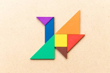 Kuş şekli ahşap arka plan üzerinde uçan renk tangram bulmacanın