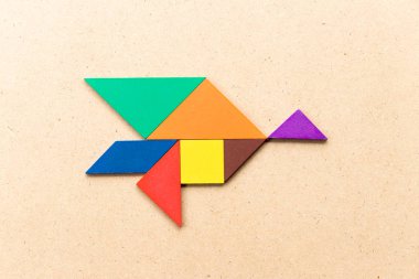 Kuş şekli ahşap arka plan üzerinde uçan renk tangram bulmacanın