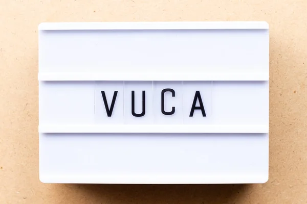 Lightbox ze słowem VUCA (skrót od zmienności, niepewności, złożoności i dwuznaczności) na tle drewna — Zdjęcie stockowe