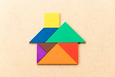 Ahşap arka planda ev veya ev şeklinde renk tangram bulmaca