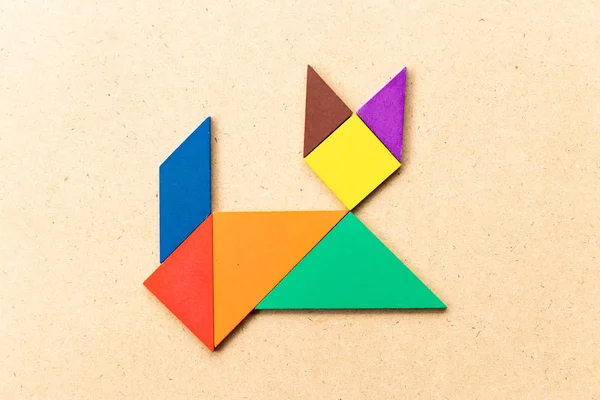 Rompecabezas tangram de color en forma de gato acostado sobre fondo de madera —  Fotos de Stock