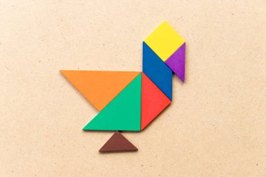 Renk tangram bulmacanın ahşap arka plan üzerinde ördek, kuğu veya kaz şeklinde
