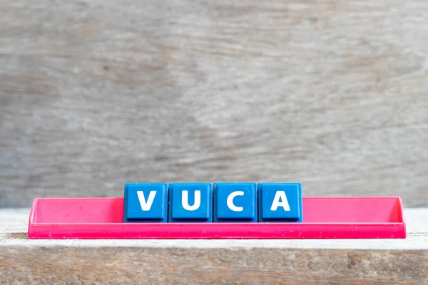 在木材背景上用文字 Vuca（波动性、不确定性、复杂性和歧义的缩写）在红色机架上的磁贴字母 — 图库照片