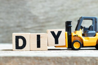 Word DIY tamamlamak için oyuncak forklift tutun mektup blok Y (kısaltma kendin yap) ahşap arka plan üzerinde