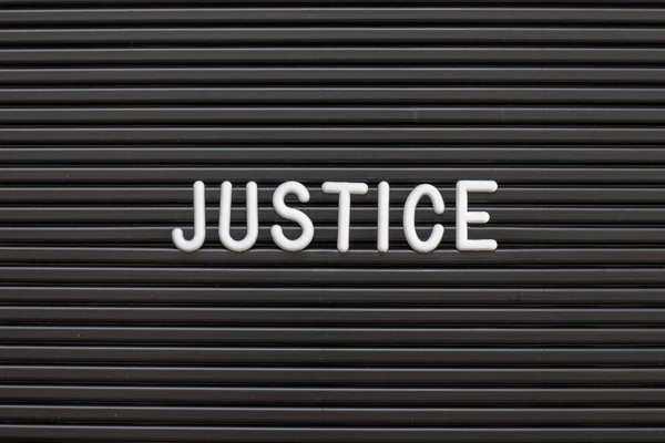 Black color felt letter board with white alphabet in word justice background