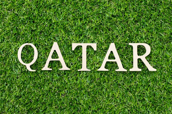 Legno alfabeto lettera in parola Qatar su sfondo erba verde — Foto Stock