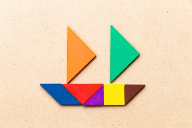 Ahşap arka planda yelkenli tekne şeklinde renk tangramı (Konsept 