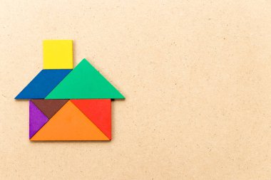 Ahşap arka planda ev veya ev şeklinde renk tangram bulmaca