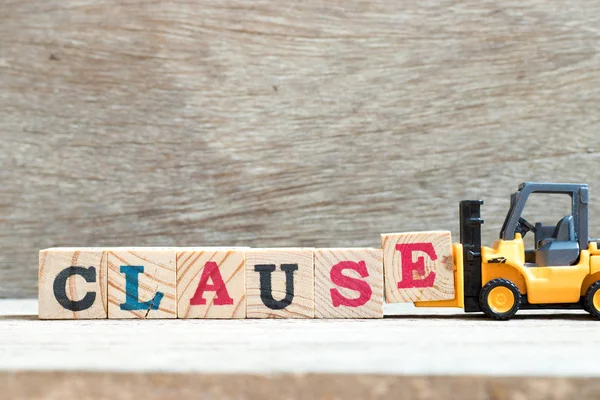 Spielzeuggabelstapler halten Buchstabenblock e, um Wortklausel auf Holzhintergrund zu vervollständigen — Stockfoto