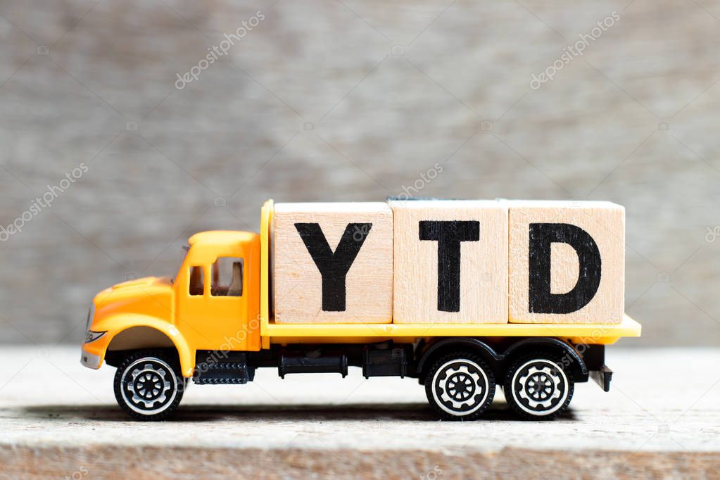 Truck hold letter block in word YTD (abbreviation of year to date) on wood background