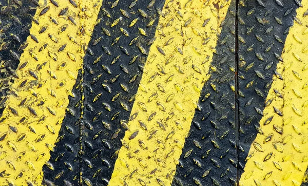 Black and yellow line paint on non-slip metal textured background