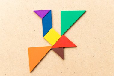 Kuş şekli ahşap arka plan üzerinde uçan renk tangram bulmacanın