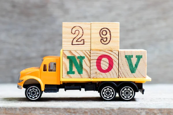 LKW halten Buchstabenblock in Wort 29nov auf Holz Hintergrund (Konzept für Datum 29 Monat November) — Stockfoto