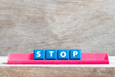 Kırmızı raftaki döşeme harfi ahşap arkaplanda duruyor.