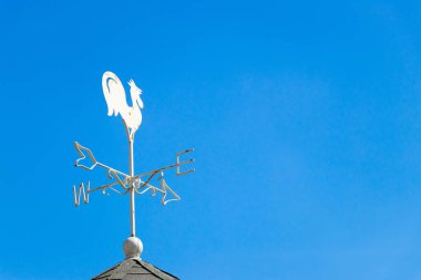 Beyaz horoz weather vane Haritayı mavi gökyüzü arka plan üzerinde rüzgar yönü