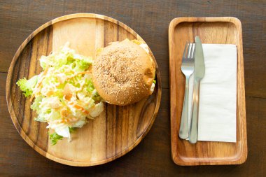 Ahşap tabakta sebze salatalı kızarmış balık fileto burger.