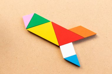 Ahşap arka planda roket ya da füze şeklinde renk tangramı yapbozu (Yeni deneyim için kavram, işe başlayın)