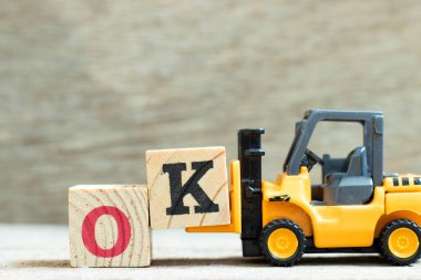Oyuncak forklift harf blok tamamlamak için k Tamam ahşap arkaplan