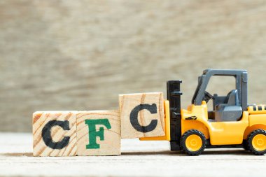Alfabe harfini tamamlamak için oyuncak forklift harf bloğunu tahta zemin zemininde CFC (klorofluorokarbonun kısaltması) ile tamamla