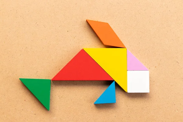 Ahşap arka planda sazan balığı şeklinde renkli tangram yapbozu