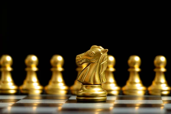 Gold knight chess piece stand in front of pawn on black background (Concept of leadership, management)