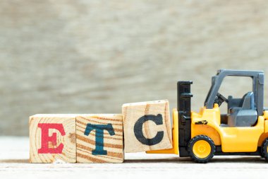 Oyuncak forklift, ahşap arkaplan üzerinde kelime tamamlamak için c harfi blok vs. (vs. kısaltması) tutun