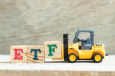 Ahşap zemin üzerinde ETF (Borsa Fonu kısaltması) sözcüğünü tamamlamak için oyuncak kaldırma engeli