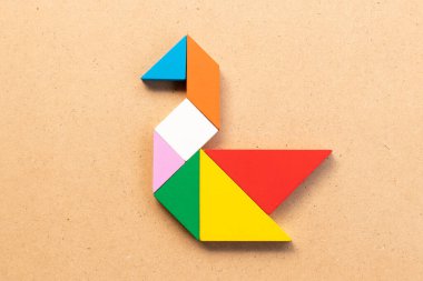 Kuğu şeklinde renkli tangram yapbozu veya ahşap arka planda ördek şekli