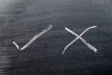 Siyah tahta arka planında doğru ve yanlış şekil işaretli beyaz tebeşirli el çizimi