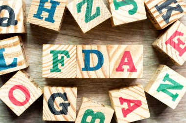 Kelime FDA ile alfabe harfi bloğu (gıda ve uyuşturucu yönetiminin kısaltması) ve ahşap arka planda bir diğeri