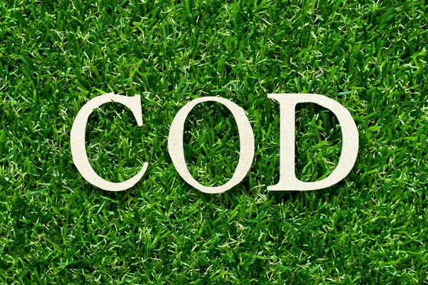 Wood alphabet letter in word cod (cash on delivery or cash on demand) on green grass background