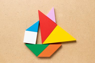 Ahşap arkaplanda yelkenli teknesi şekilli renk tangramı bulmacası (Girişimci ya da girişimci konsepti)