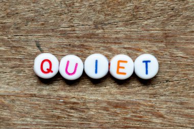 Beyaz boncuk, ahşap arka planda sessiz harflerle yazılmış.