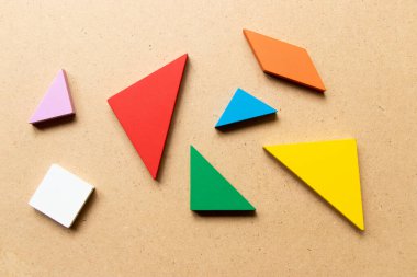 Ahşap arkaplanda biçimi tamamlamak için bekleyen renk tangramı bulmacası